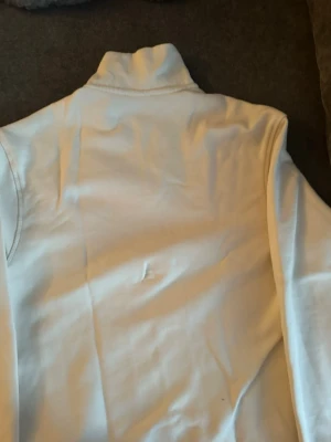 Vit stickad tröja med quarter zip - Vit stickad tröja med hög krage och half zip-dragkedja framtill. Tröjan har lång ärm och en stilren, enkel design som passar perfekt till många olika outfits.helt nytt oanvänd 