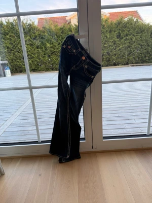 Mörkblå bootcut jeans True Religion - Säljer ett par limited edition mörkblå bootcut jeans från True religon då dom inte kommer till användning. Ny pris 2700kr men säljer för 999kr då dom är i mycket bra skick. Storlek 23. 
