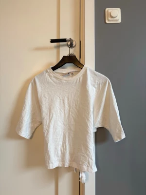Vit kortärmad topp med knyt - Vit topp med rund halsringning, korta ärmar och knyt i ryggen.