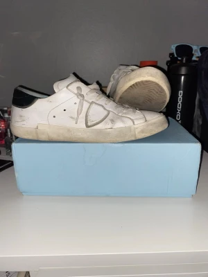 Vita sneakers från Philippe model - Klassiska vita Philippe model sneakers i lågt snitt med gröna detaljer på hälen. Skorna har vita snören, diskreta hål för ventilation på sidan och en robust gummisula. Tillverkade i läder för en clean och stilren look som passar till det mesta.