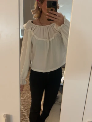 Vit volangblus med lång ärm - Söt vit blus med volangdetaljer och rundad halsringning från Kappahl. Helt oanvänd. Skriv om ni har frågor💕