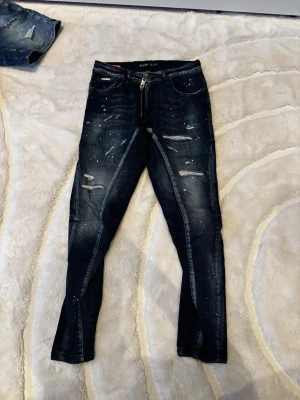 Blåa Slitna Jeans - Snygga mörkblå skinny jeans från Black Island med slitningar, färgstänk och dragkedja i gylfen. Helt nya och oanvända. Endast för 300kr. Hör av dej vid intresse! 🙂