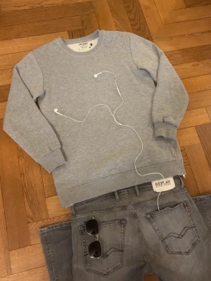Grå sweatshirt från Jack & Jones - Grym kvalité, inga defekter. Storlek är L, passformen sitter bra. Men Kolla måtten så de passar:)  Mått -|-  Axelmått: 45 cm  Längd: 71 cm  Bröst: 54 cm  Arm: 59 cm  Leverans sker dagen efter, men har du nån fråga är det bara att skriva :)