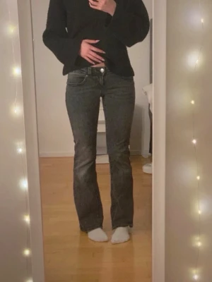 Mörkgrå bootcut jeans med fickdetaljer - Säljer ett par mörkgrå bootcut jeans med snygga fickdetaljer bak och vita knappar. Jeansen har klassisk femficksmodell och är tillverkade i ett stretchigt denimtyg som sitter bekvämt. Perfekta för dig som vill ha snygga och bekväma jeans! Jeansen har inget slitage eller större tecken på användning. Kontakta mig om ni undrar något eller vill ha fler bilder!💗