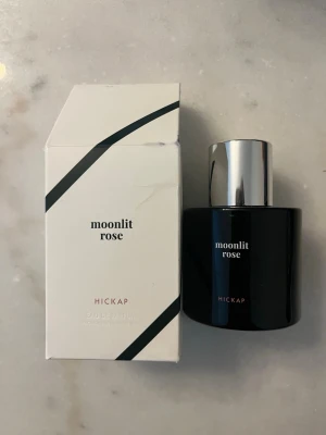 Moonlit Rose parfym från Hickap  - Parfym från Hickap endast testad.                 Moonlit Rose från Hickap är en elegant parfym i svart flaska med silverfärgat lock. Förpackningen är stilren i vitt med svarta diagonala linjer och minimalistisk text. Perfekt för dig som gillar moderna och sofistikerade dofter.