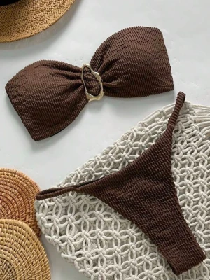 Brun bandeau bikini med ringdetalj - Snygg brun bandeau bikini med ribbad struktur och guldfärgad ringdetalj framtill. Överdelen knyts i ryggen och bikinitrosan är en string modell. Denna bikini är ALDRIG använd såklart💕