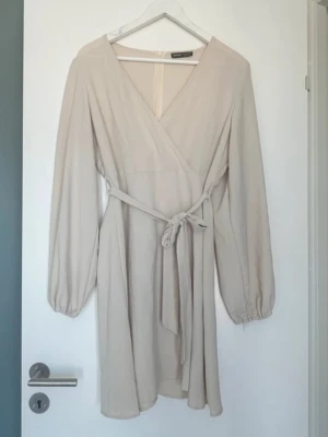 Klänning beige  - Säljer en känning som endast är använd en gång. Faller superfint på kroppen. 