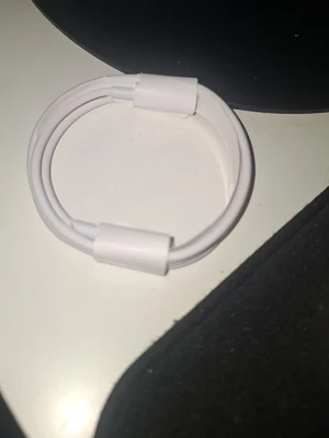 Vit laddningskabel USB-C - Säljer en vit laddningskabel med USB-C-kontakter i båda ändar. Kabeln är rund och flexibel, perfekt för att ladda eller synka olika enheter. Passar till många moderna smartphones, surfplattor och laptops.