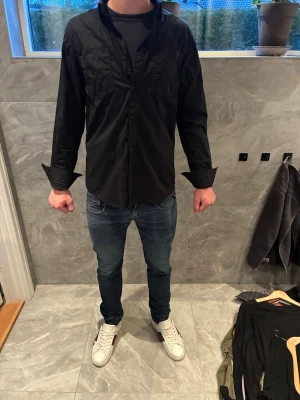 Svart skjorta från G-Star Raw XL - Säljer en svart skjorta från G-Star Raw i storlek XL. Skjortan har klassisk krage, knappar framtill och lång ärm. Tillverkad i mjuk bomull som känns skön mot huden. Perfekt för dig som gillar en stilren och enkel look.
