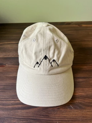 Keps, HM - Off-White keps med broderade berg. 