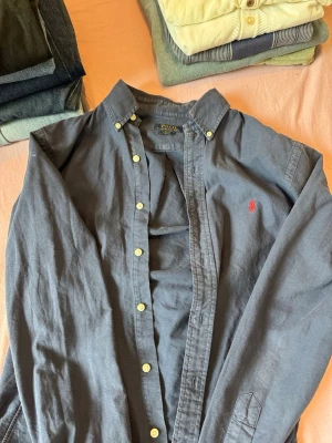 Mörkblå skjorta från Polo Ralph Lauren - Klassisk mörkblå skjorta från Polo Ralph Lauren med röd broderad logga på bröstet.