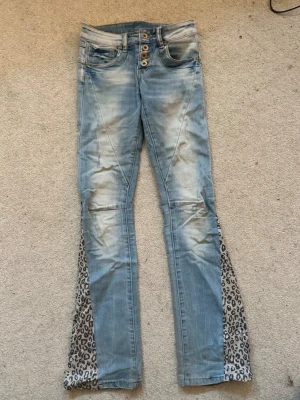 Ljusblå utsvängda jeans med leoparddetaljer - Jättesnygga jeans köpta på Vinted som tidigare ägare har sytt om själv. De är väldigt lågtmidjade och passar tyvärr inte mig, därför säljer jag dem vidare. Pris kan diskuteras vid snabb affär. Jeansen säljs billigare på min Vinted- alicestuder ❣️