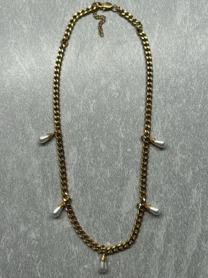 Guldhalsband med droppformade pärlor WOS - Supertrendigt och snyggt halsband från WOS. Halsbandet är guldpläterat rostfritt stål. Totallängden är 51 cm men går att justera kortare. Halsbandet är endast använt en gång. Nypris 800kr. Säljer även matchande örhängen!