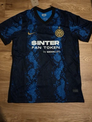 Inter Milan matchtröja Nike blå - Snygg Inter Milan matchtröja från Nike i blått och svart med ormliknande mönster. Tröjan har klubbmärke och Nike-logga på bröstet samt sponsortryck framtill. Perfekt för fotbollsfans som vill sticka ut på planen eller läktaren. Priset kan diskuteras 