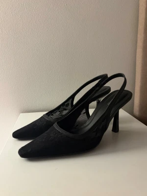 Svarta spetsiga klackar - Snygga svarta klackar från Zaralndo med rem och är täckta i ett elegant spetsmaterial med blommönster. Perfekta för att lyfta din outfit med en stilren och trendig touch. Helt nya andvända en gång, säljer då jag köpte fel storlek 