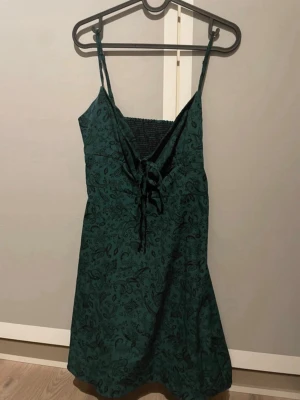 Grön klänning med mönster - Grön klänning med mönster från shein i storlek s! Klänningen har ribbat typ i ryggen och dragkedja på sidan, lappen med tvättråd är tyvärr bortklippt men den är i gott skick och sparsamt använd!