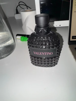 Valentino Born in Roma EDP - Snygg parfymflaska från Valentino i svart glas med coolt nitat mönster och matt svart kork. Flaskan har en lyxig och modern design med Valentino-loggan i rosa på svart band runt flaskan. Perfekt för dig som gillar exklusiva  dofter och stilren look. Ca 90 ml kvar knappast använd 