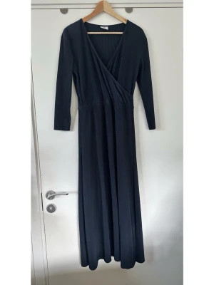 Mörkblå långklänning med omlott, storlek M - Snygg lång navy / marinblå klänning / omlottklänning från Kauf Dich Glücklich i storlek M. Populära modellen ”Lydi Dress” med långa ärmar och V-ringning. Klänningen har en plisserad textur och en markerad midja med resår för bästa passform. Mycket gott skick, som ny!