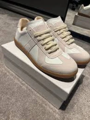 Vita sneakers med beige detaljer - Stilrena sneakers i vitt med beige detaljer och gummisula. Ovandelen är i en mix av mocka och textil, med klassisk snörning och låg profil. Perfekta för dig som gillar minimalistisk och clean stil.