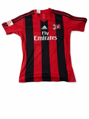 AC Milan matchtröja Adidas röd/svart från säsongen 2013-14 - Pris går att diskutera, skicka gärna bud          Snygg AC Milan matchtröja från Adidas i rött och svart med klassiska ränder. Tröjan har klubbmärke, sponsorloggor och korta ärmar. Perfekt för fotbollsträning eller att bära på läktaren. Materialet är lätt och andas bra.