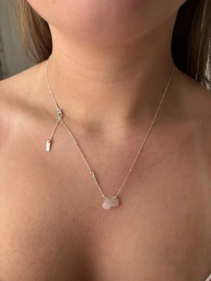 Silvrigt halsband med kristall - Från Pilgrim! Stenen är Rose quartz och halsbandet är aldrig använt, kedjan är justerbar 🫶💞