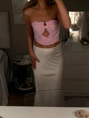 Rosa bandeau tubtopp med cut-out - Trendig rosa bandeau tubtopp i frotté med snygg cut-out framtill och twistad detalj. Toppen är axelbandslös och har en cool, croppad passform som passar perfekt till sommarens outfits.