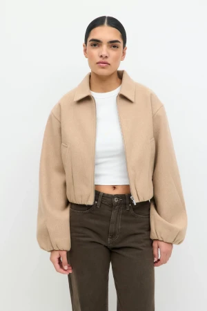 Kort beige ullrock med ballongärm - Säljer en trendig kort beige rock med dragkedja och ballongärmar. Rocken har klassisk krage, elastisk midja och är tillverkad i ett mjukt ullmaterial. Perfekt för dig som gillar en clean och modern look.