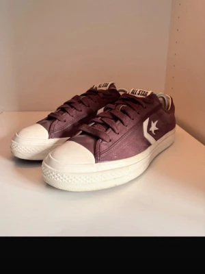  Converse Star Player 76 - Snygga vinröda Converse One Star sneakers med vit sula. Klassisk låg modell med tåhätta i gummi och matchande vinröda skosnören. Perfekta för dig som gillar retrostil och streetwear.