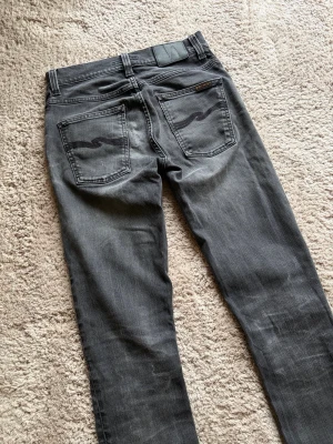 Nudie Jeans Grim Tim Black Worn - Modell: Grim Tim🪬  Färg: Svart/Grå🪬  Storlek: W29 L34 🪬  Mått: W36cm L110cm Benöppning 15cm 🪬  Skriv vid minsta fundering!🪬