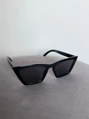 Svarta clean y2k cat eye-solglasögon från Lindex - Svarta trendiga solglasögon från Lindex. Kantig modell med mörka glas. Sparsamt använda, fint skick. Perfekta till våren och sommaren! ☀️