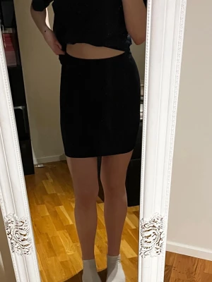 Svart tight kortkjol - En enkel och stilren svart kortkjol med tight passform. Kjolen har en rak siluett och är gjord i ett mjukt stretchigt material som sitter snyggt på kroppen. Perfekt att matcha med crop tops eller oversized tröjor.