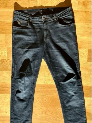 Hansen and Jacob slim jeans - Dessa marinblå slim-fit jeans från märket Hansen & Jacob är av modellen Cape Town. Storleken är (W34 L34), men det rekommenderas att kontrollera de exakta måtten före köp för att säkerställa rätt passform. 📏 Midjebredd (platt): 44 cm Total längd: 115 cm Bredd vid benslut: 17 cm Som referens är modellen på bilden 190 cm lång och väger 80 kg. 