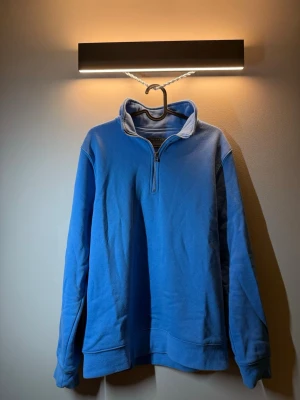 Blå halvzip hoodie från Primark - En blå hoodie från Primark med halv dragkedja framtill och hög krage. Hoodien har en avslappnad passform och är gjord i mjukt bomullsmaterial. Perfekt för en chill och casual look.