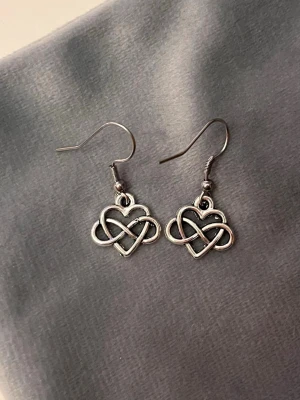 Örhängen Hjärta med evighetssymbolen silver imitation   - Fina örhängen med ett hjärta och tecknet för evighet. Berlockerna är ca 1 x 1,5 cm.