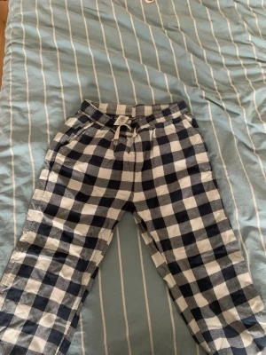 Rutiga mjukisbyxor med dragsko - Säljer ett par mjukisbyxor med svartvitt rutigt mönster och elastisk midja med dragsko. 