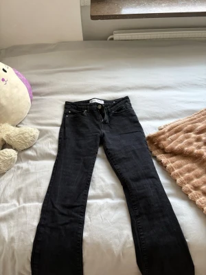 Svarta lågmidjade jeans från Bershka bootcut - Säljer ett par svarta bootcut jeans från Bershka. Jeansen har klassisk femficksdesign, hällor för skärp och stängs med knapp och dragkedja. Perfekta för dig som gillar en tidlös och clean look.