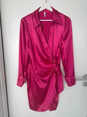 Omlottklänning i satin - Fin omlottklänning i satin i strl s. Endast använd 1 gång så är i jättefint skick. Märket är okänt.