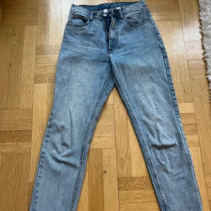 Blå high waist mom jeans - Ett par klassiska blå mom jeans med hög midja och raka ben. Jeansen har fem fickor, bälteshällor och stängs med knapp och dragkedja. M men mer som S, aldrig använda då de är för korta för mig.