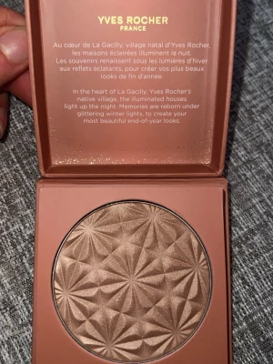 NY Yves Rocher Poudre Bronzante Nacrée - Snygg bronzer från Yves Rocher i nyansen Poudre Bronzante Nacrée. Kommer i en brun, fyrkantig ask med gulddetaljer och ett vackert mönstrat puder i skimrande bronsfärg. Perfekt för att ge ansiktet en solkysst glow med pärlemorskimrande finish.