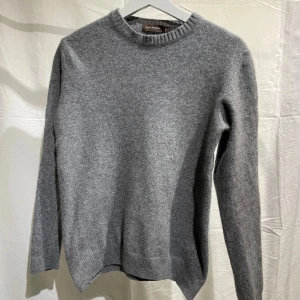 Grå cashmeretröjafrån Oscar Jacobson - Säljer en stilren grå cashmeretröjafrån från Oscar Jacobson. Tröjan är i M men passar bättre XS/S då den råkats tvätta i för höga grader och krympt i storlek.