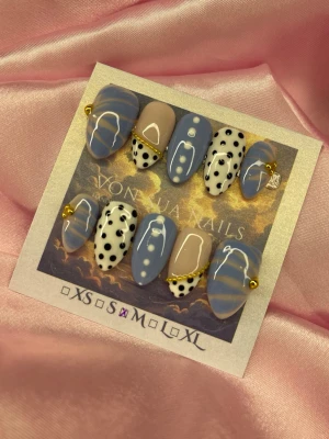 BlueBijou (M);Short Almond - Snygga handgjorda press-on naglar i en kort mandelform. Mix av ljusblå, nudebeige och vita naglar med svarta prickar, guldiga detaljer. Unik design med både prickigt och guldigt, perfekta för dig som vill sticka ut.M: 16 mm, 12 mm, 12,5 mm, 11,5 mm, 10 mm