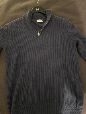 Marinblå halvzip från John Henric - Säljer en marinblå stickad tröja från John Henric med halv dragkedja och hög krage. Tröjan är ribbstickad och har långa ärmar, perfekt för lager på lager och en stilren look. Passar dig som gillar klassisk och enkel stil. Nypris omkring 1500 kr 