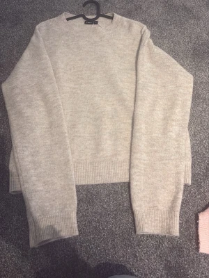 Beige stickad tröja från LMTD - Mysig beige stickad tröja från LMTD i storlek M (15-16 år). Tröjan har rund halsringning, långa ärmar och ribbade muddar vid ärmslut och nederkant. Perfekt för lager på lager och enkel att matcha med olika outfits.