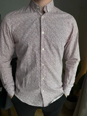  skjortor Zara/tailoredoeiginal - Säljer två stilrena skjortor med småblommigt mönster, en i vitt med blå detaljer och en i vitt med röda detaljer. Båda har klassisk krage, knappar framtill och lång ärm. Perfekta för dig som gillar en fräsch och trendig look.           USA:M -Slim fit 