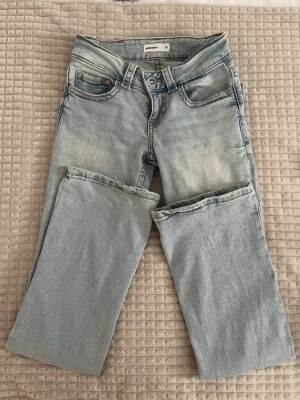 Ljusblå jeans från Gina Tricot - Säljer ett par ljusblå jeans från Gina Tricot med klassisk femficksdesign och raka ben. Jeansen har dragkedja och knapp framtill, samt subtila slitningar för en cool look. Perfekta för dig som gillar en avslappnad stil. Jag är 160cm lång och dessa jeansen passade mig när jag vägde 52kg och även nu när jag väger 56kg