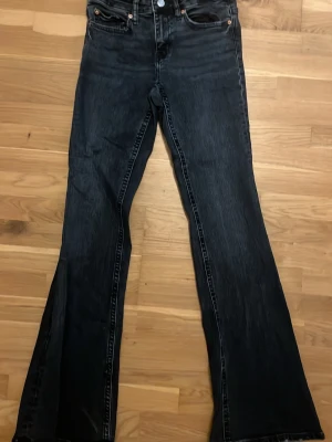 Mörkblå bootcut jeans - Säljer ett par mörkblå bootcut jeans med klassisk femficksdesign och snygga kontrastsömmar. Jeansen har en hög midja och är tillverkade i denim med lätt tvättad look. Perfekta för dig som gillar en retrostil och vill ha ett par jeans som sticker ut. Söndriga vid slutet av jeansen då ja gått på dom