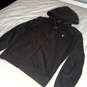 Svart hoodie från Polo Ralph Lauren - Säljer en snygg svart hoodie från Polo Ralph Lauren. Den har en dragkedja framtill och en klassisk logga på bröstet. Hör av dig vid funderingar eller frågor! Nypris 2100 mitt pris 450