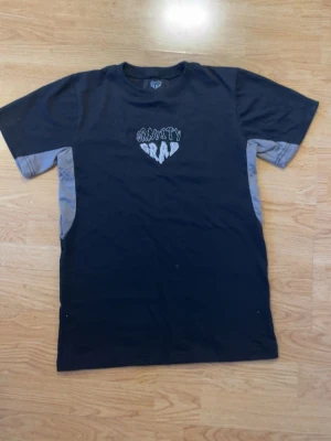 Svart Gravity Grab t-shirt - Cool svart t-shirt från Gravity Grab med gråa paneler på sidorna och ärmarna. Tryck på bröstet med texten 'Gravity Grab' i vitt. Klassisk passform och rund hals. Perfekt för en avslappnad streetwear-look. Helt ny! Aldrig använd! Bara utan tagg😁