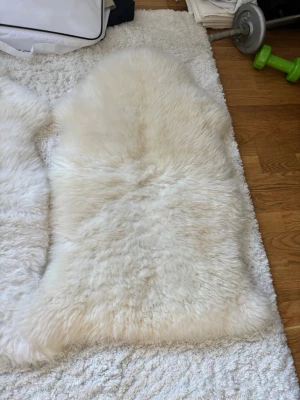 Vita 2 st  fårskinn - Två mjuka och fluffiga fårskinnsfällar i vit färg. Perfekta att ha som inredningsdetalj på golvet, i soffan eller över en stol. Fällarna har naturlig form och lång, tät päls som ger en mysig känsla till rummet.
