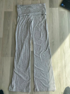 Grå mjuka yoga-byxor med låg midja - Säljer ett par grå yoga-byxor med låg, vikbar midja och utsvängda ben. Tillverkade i ett mjukt och stretchigt material som är bekvämt att bära. Enkel design utan synliga loggor eller fickor. I storlek 146/152